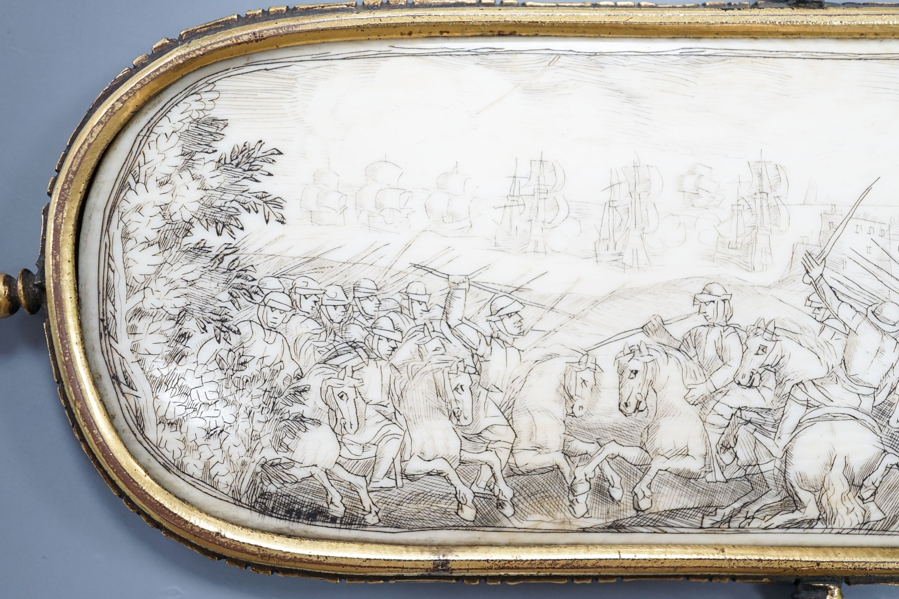 A 17th century French oval ivory plaque in a revolving metal surround, etched on both sides with battle scenes and ships in the background 17cm